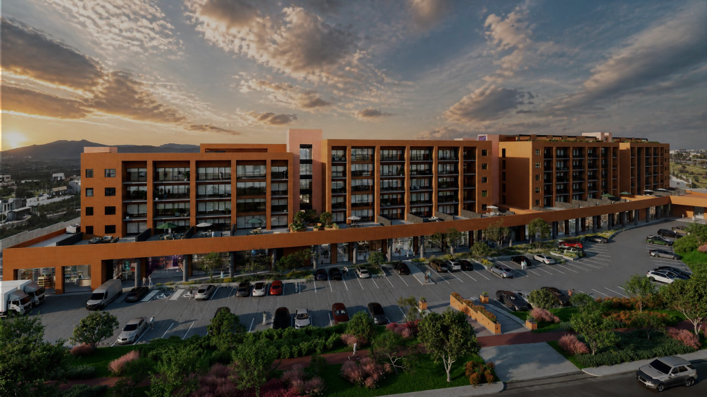 A modern orange apartment complex at sunset with a large parking lot in the foreground.
